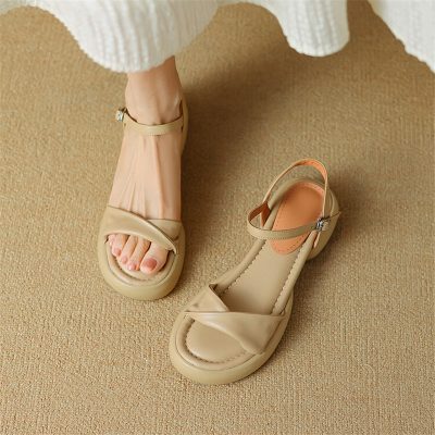 Elegant beige ankle strap sandals for women on neutral carpet background.