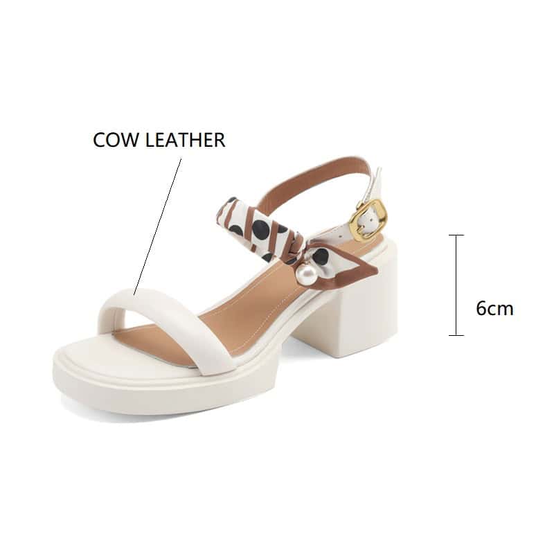 Stylish white sandal with cow leather straps, adjustable strap with gold buckle, and decorative pearl accent, perfect for fashion-conscious women.