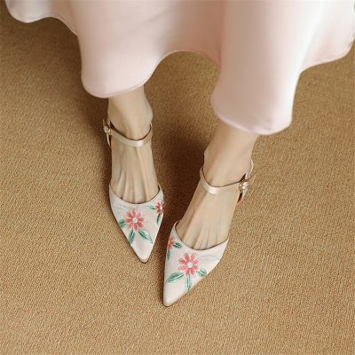 Stylish white high-heeled shoes with pink floral embroidery and ankle straps, perfect for fashionable women.