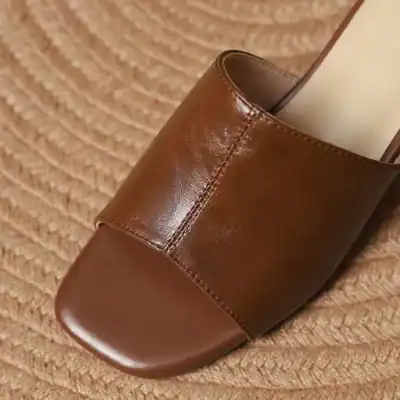 High-quality brown leather slide sandals featuring sleek design and comfort, perfect for everyday wear and stylish occasions.