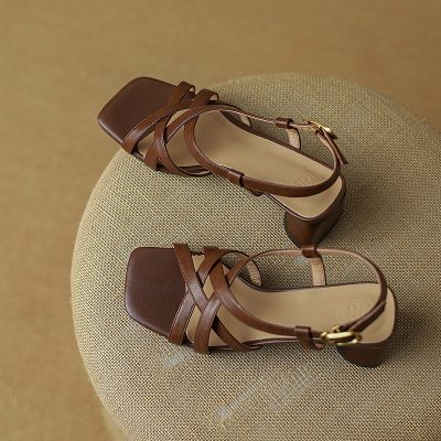 Elegant brown women's heeled sandals on beige surface.