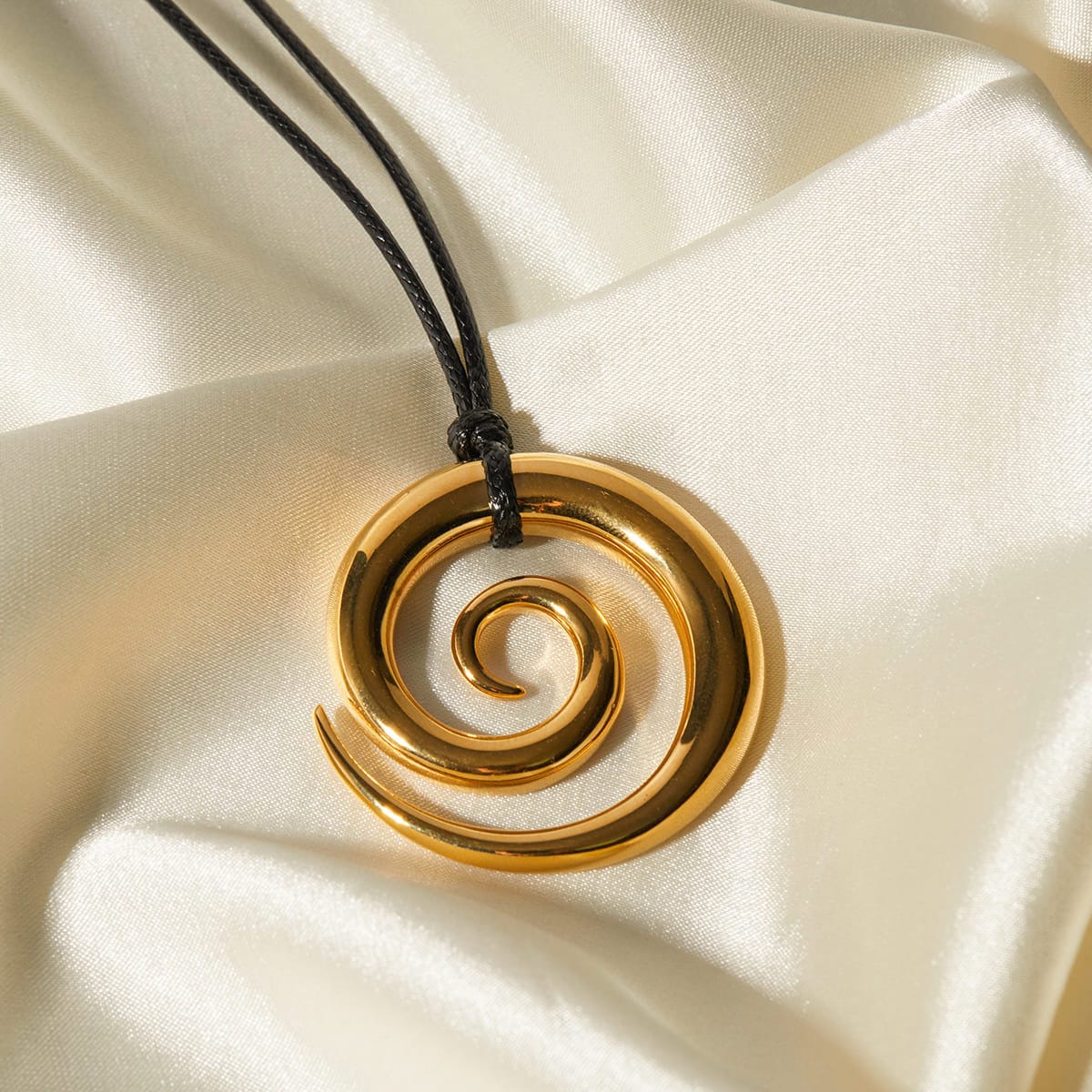 Golden spiral pendant on black cord, luxurious jewelry accessory for women, perfect for fashion and statement looks.