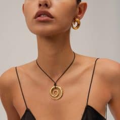 Close-up of a woman wearing a gold spiral pendant necklace and matching gold earrings, showcasing stylish and luxurious jewelry by Monalisa Store. Perfect for enhancing your fashionable look.