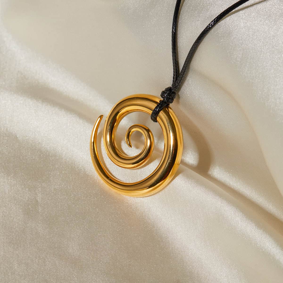 Elegant gold spiral pendant necklace with black cord, perfect for stylish jewelry accessories and fashion statements.