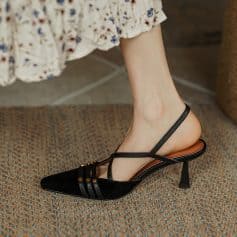 Elegant black high-heeled pump with pointed toe, thin ankle straps, and decorative accents, perfect for fashionable footwear and formal occasions.