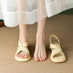 Close-up of beige women's sandals with comfortable straps on a person's feet, showing a relaxed indoor setting, perfect for casual or summer wear.