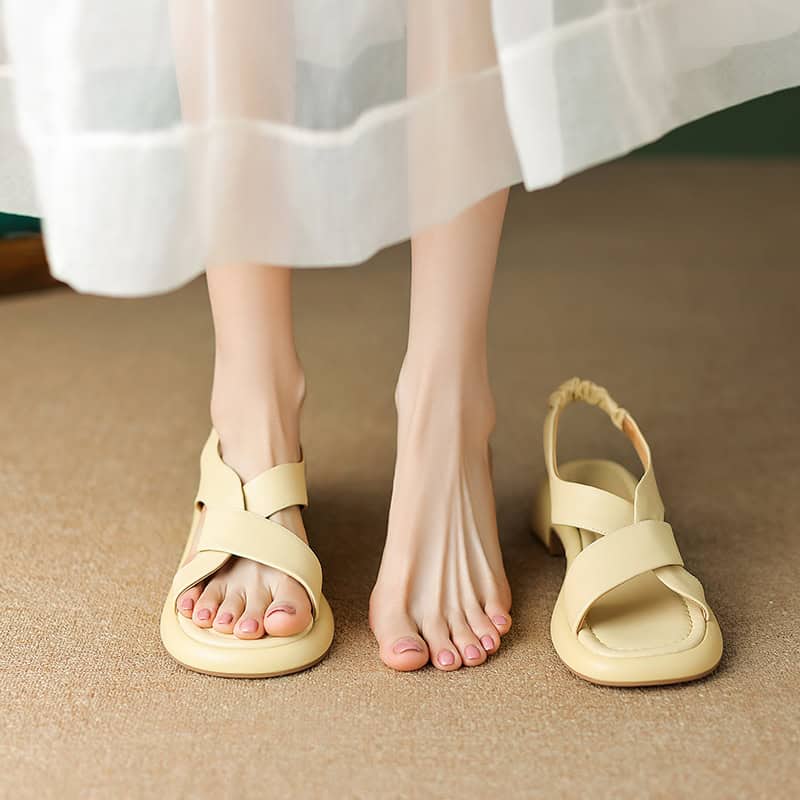Close-up of beige women's sandals with comfortable straps on a person's feet, showing a relaxed indoor setting, perfect for casual or summer wear.