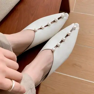 White slip-on shoes with pearl embellishments, perfect for stylish everyday wear or special occasions. Comfortable and chic footwear with a sophisticated design.