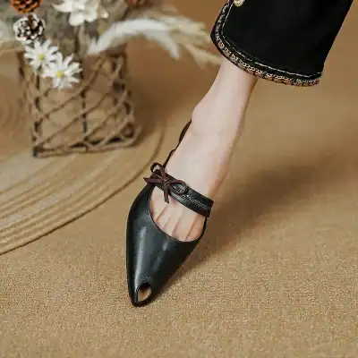 Elegant black ballet flat with ankle strap and bow detail, perfect for stylish everyday wear and comfortable walking.