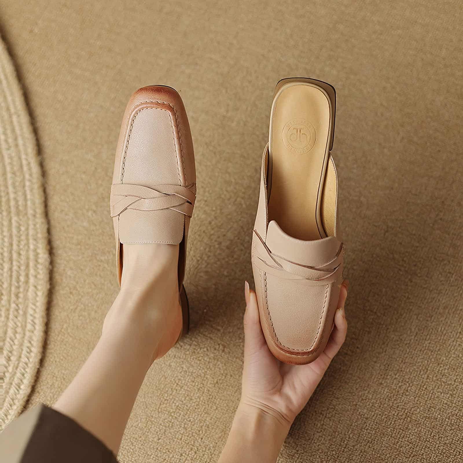 Close-up of stylish nude leather loafers displayed on a beige textured surface, showcasing handcrafted design and comfort, perfect for fashionable women seeking premium footwear.