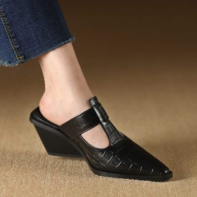 Comfortable black leather wedge mule with crocodile texture, slip-on design, and pointed toe, perfect for both casual and formal occasions.