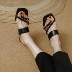 Elegant black strappy sandals with chunky ankle straps, perfect for fashion-forward women seeking comfortable yet trendy footwear options.