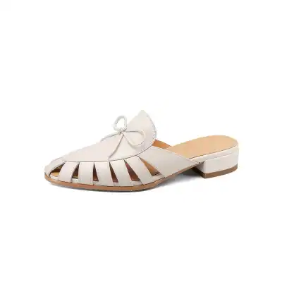 Elegant white leather slip-on sandals with a bow and cut-out design, perfect for women seeking stylish comfort and trendy footwear. Ideal for casual wear or summer outings.
