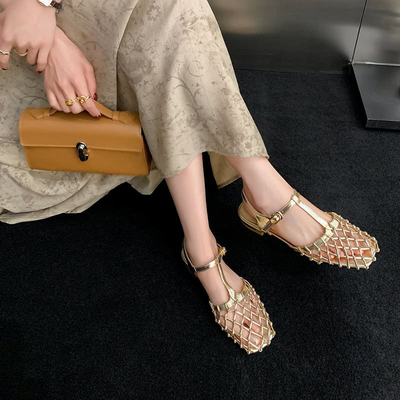 Fashionable gold sandals with intricate netted straps and ankle buckles, perfect for chic occasions, paired with a beige floral dress and matching accessories.
