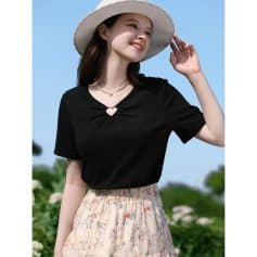 A fashionable woman wearing a black trendy top with a heart-shaped neckline detail, paired with a floral skirt and wide-brim hat, showcasing elegant summer apparel.