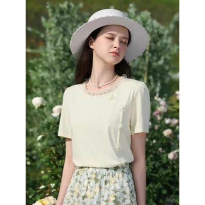 Young woman wearing a stylish white hat, light yellow top, and floral skirt in a garden setting, perfect for summer fashion, outdoor wear, and spring style inspiration.