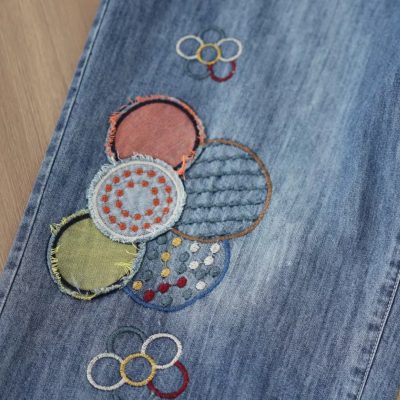 Stylish embroidered denim with vibrant circle designs and Olympic rings, perfect for casual fashion enthusiasts shopping at Monalisa Store.