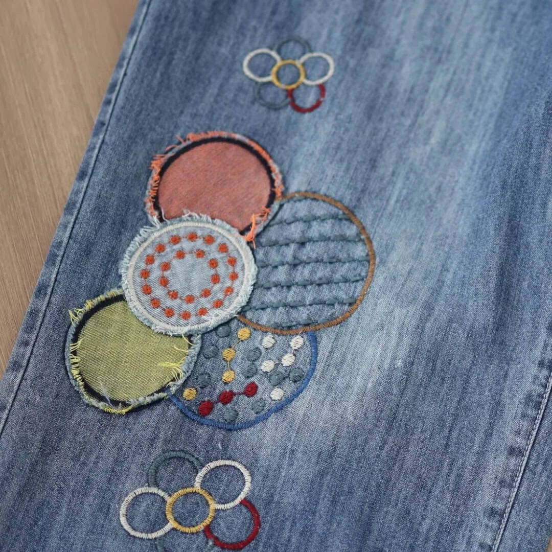 Stylish embroidered denim with vibrant circle designs and Olympic rings, perfect for casual fashion enthusiasts shopping at Monalisa Store.
