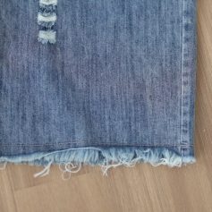 Close-up of blue denim fabric with frayed hem, showcasing trendy distressed jeans for casual wear. Perfect for stylish, comfortable fashion enthusiasts.