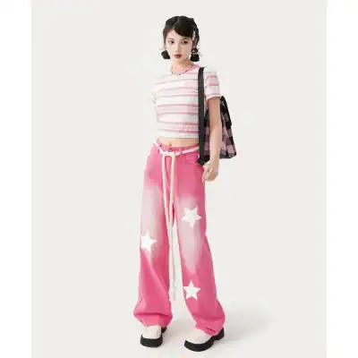 Stylish young woman with pink star-patterned pants, striped crop top, and accessories, showcasing trendy casual wear at Monalisa Store.