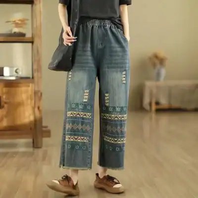 High-waisted distressed wide-leg jeans with intricate embroidery, perfect for stylish everyday wear. Features ripped details and ethnic patterns, offering a trendy and comfortable look for women.