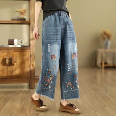 High-waisted, distressed denim pants with colorful butterfly embroidery and floral details, perfect for casual and fashionable looks. Comfortable fit with relaxed silhouette.