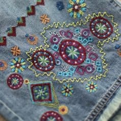 Vibrant embroidered denim patch featuring detailed geometric and floral designs, perfect for fashion accessories or decoration, showcasing craftsmanship and vibrant colors.