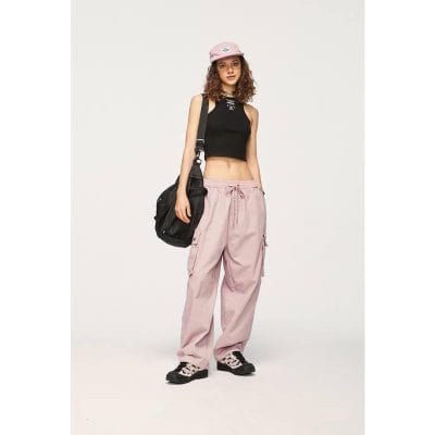 Young woman in trendy casual streetwear with pink cargo pants, black crop top, stylish pink cap, and black sneakers, shopping at Monalisa Medical Store.