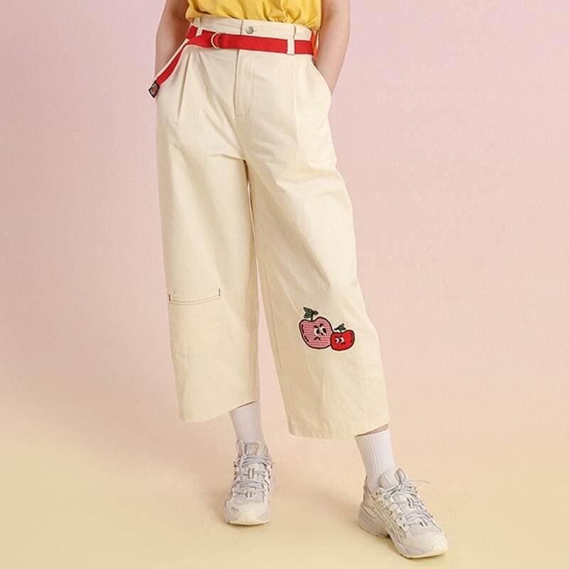 Playful cherry embroidery on cream wide-leg trousers with red belt accents, perfect for casual or trendy fashion statements.
