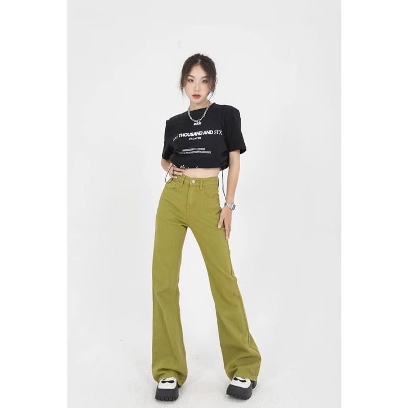 Stylish women's green high-waist jeans with casual crop top, trendy accessories, and chunky sneakers, perfect for streetwear and everyday style.
