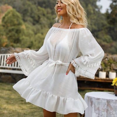 A woman wearing a stylish white dress with lace embellishments on the sleeves, ideal for summer outings or casual events. High-quality fabric, comfortable fit, and fashionable design perfect for beach or garden parties.