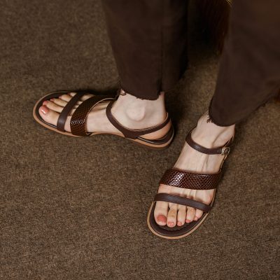Close-up of women's brown leather sandals with ankle strap, suitable for casual and everyday wear, displayed on textured brown carpet floor, from Monalisa Store.