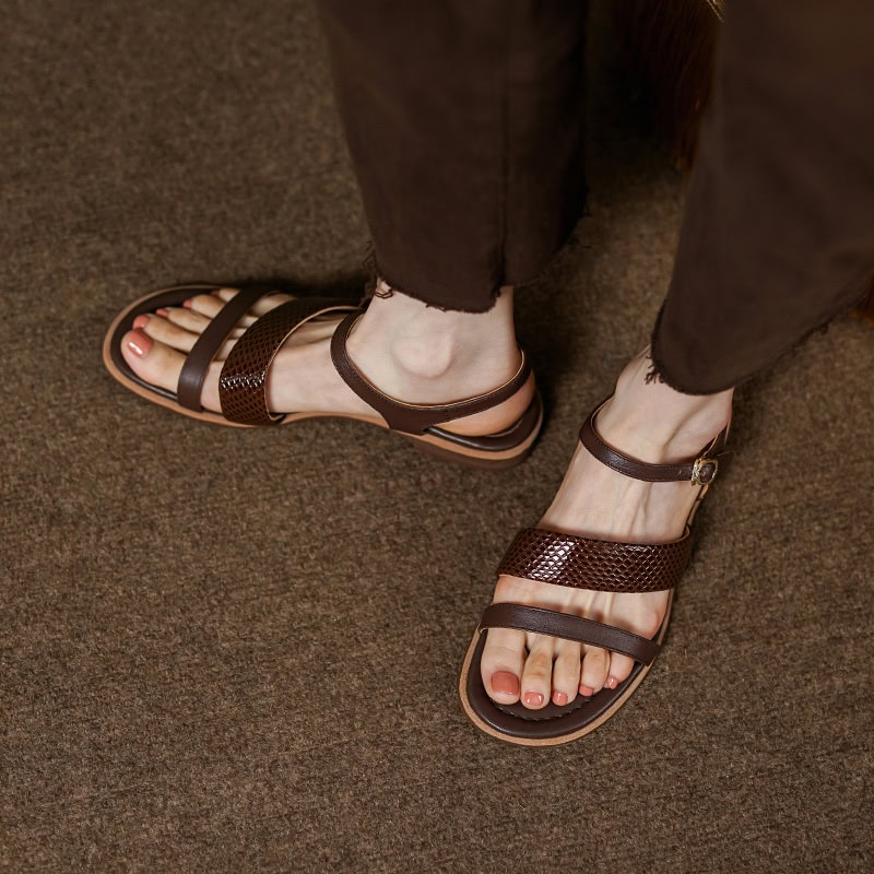 Close-up of women's brown leather sandals with ankle strap, suitable for casual and everyday wear, displayed on textured brown carpet floor, from Monalisa Store.
