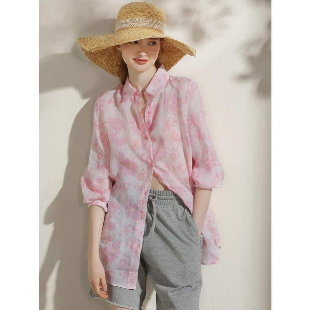 A fashionable woman wearing a wide-brim straw hat and pink floral shirt, perfect for summer outings, showcasing trendy and comfortable women's clothing.