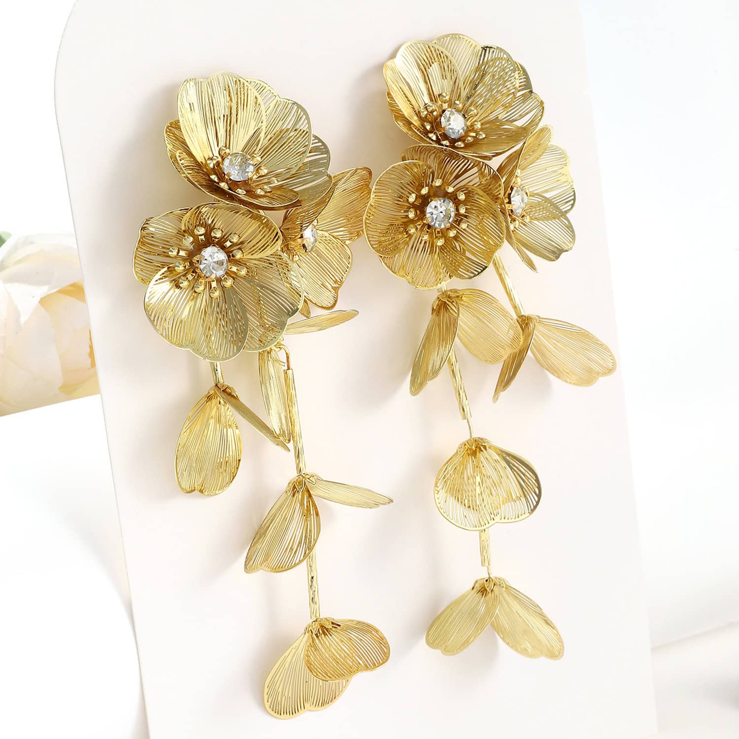 Luxurious gold flower-shaped earrings adorned with sparkling crystals, featuring intricate petal details and dangling leaf accents for sophisticated style. Perfect for special occasions or elegant accessories.