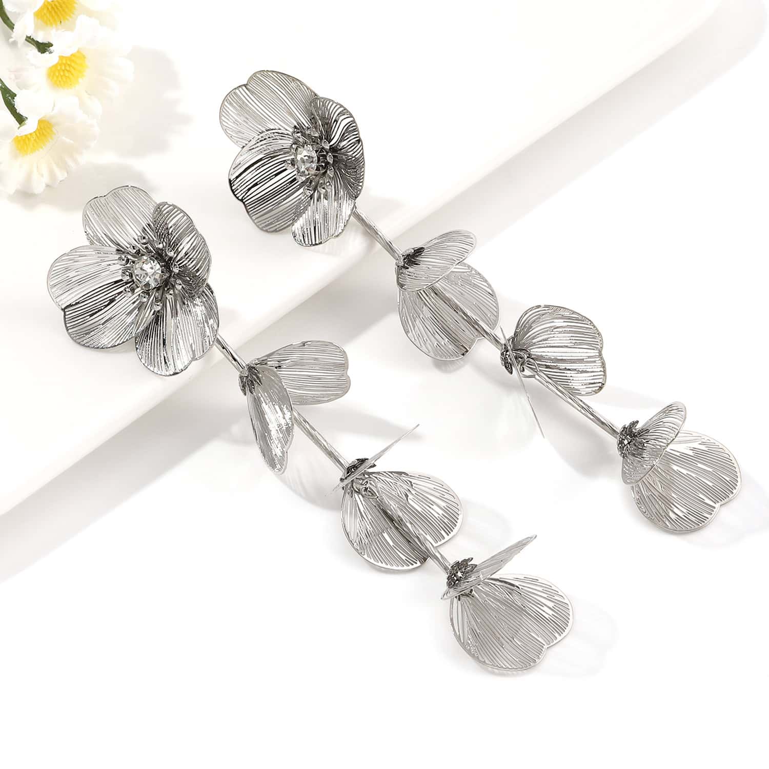 Sterling silver floral earrings with intricate petal design and sparkling rhinestone accents, perfect for stylish accessories and jewelry lovers.