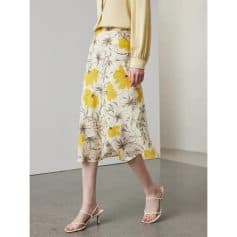 Stylish women's floral midi skirt with yellow and brown flower pattern, perfect for spring and summer occasions, paired with heels for a chic look.
