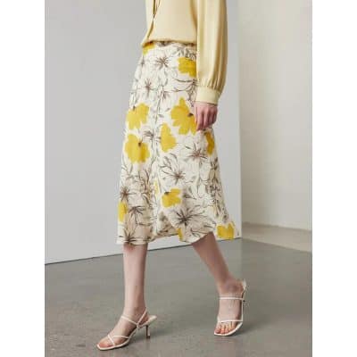 Stylish women's floral midi skirt with yellow and brown flower pattern, perfect for spring and summer occasions, paired with heels for a chic look.