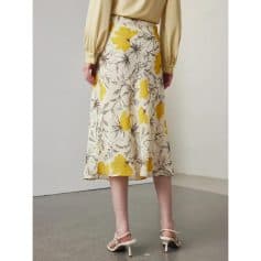 High-waisted floral midi skirt featuring vibrant yellow flowers and grey leaf designs, perfect for stylish summer or spring outfits.