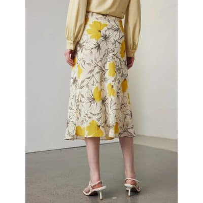 High-waisted floral midi skirt featuring vibrant yellow flowers and grey leaf designs, perfect for stylish summer or spring outfits.