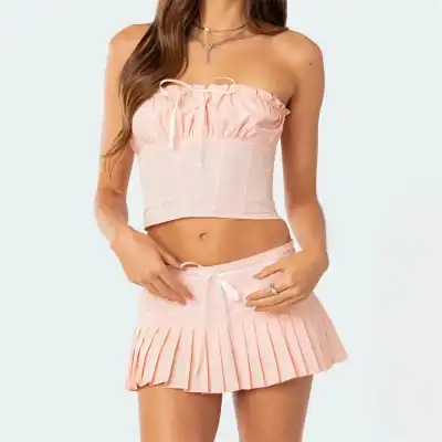 Comfortable pink satin sleepwear for women, featuring a strapless crop top and pleated mini skirt, perfect for relaxing or casual wear.
