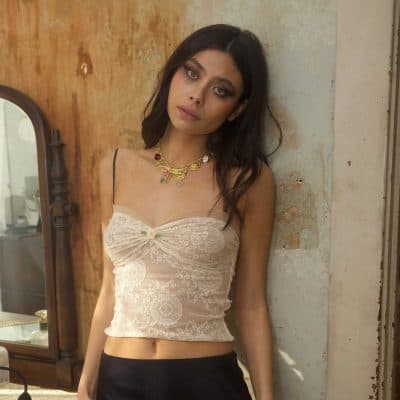 Elegant lace crop top with intricate details, styled with a statement necklace, perfect for fashionable women's outfits.
