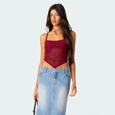 A stylish woman wearing a sheer maroon tank top and a high-waisted, acid-wash denim skirt, accessorized with a black choker and gold jewelry. Perfect for trendy, casual outfits and summer looks.