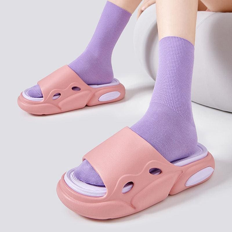 Pink slide sandals with purple socks, trendy and comfortable footwear for casual and leisure wear. Perfect for relaxed style and foot health.