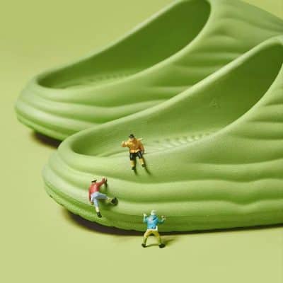 Miniature people climbing rubber slip-on shoes, emphasizing comfort and style in everyday footwear. Perfect for a casual, trendy look with easy slip-on convenience.