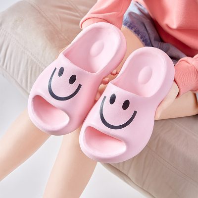 Pink cartoon smiley face slippers for kids, comfortable and fun indoor footwear with a playful design and soft sole, perfect for children to wear around the house for comfort and style.