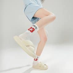 Cream-colored slides with trendy socks featuring a sports theme, showcasing casual yet fashionable footwear for everyday wear, ideal for a modern, youthful look.
