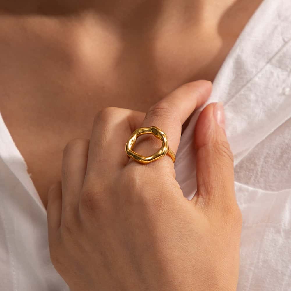 Close-up of a gold ring with an organic, wavy design worn on a woman's finger, highlighting stylish jewelry from Monalisa Store. Perfect accessory for enhancing your look.