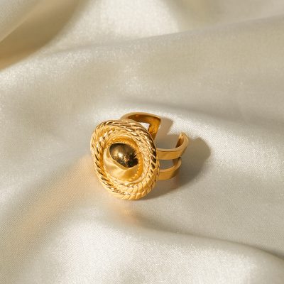Luxury gold ring featuring intricate woven design and a central spherical element, displayed on smooth satin fabric for upscale style and jewelry showcase.