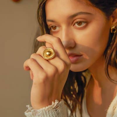 Close-up of a woman wearing a bold gold ring, showcasing luxury jewelry that enhances sophisticated style.
